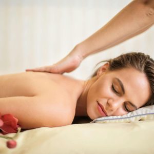 Topless Woman Lying on Bed Getting Massage
